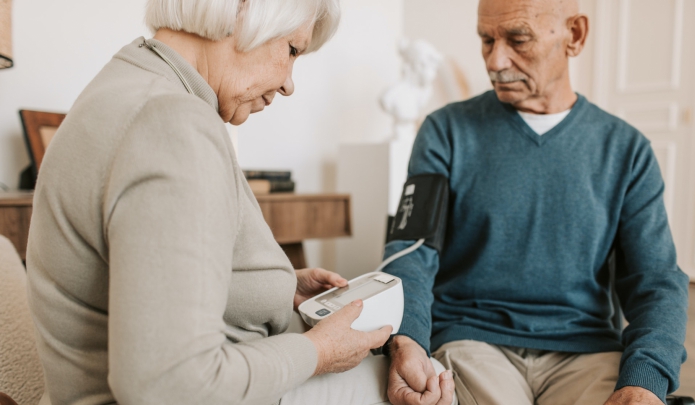 Older spouse taking husband's blood pressure.