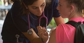 nurse with a stethoscope giving a shot to a young patient