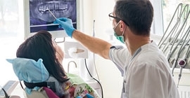 A dental student shows a patient an X-ray of her teeth